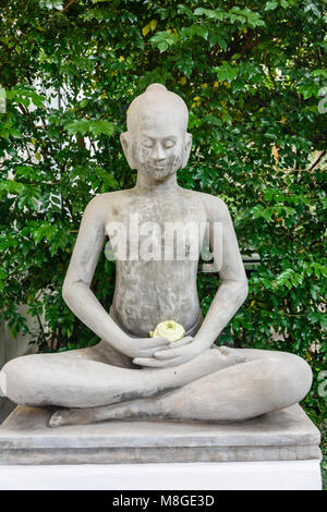 Stein Statue von Buddha mit Lotus Blume in einem Garten Stockfoto