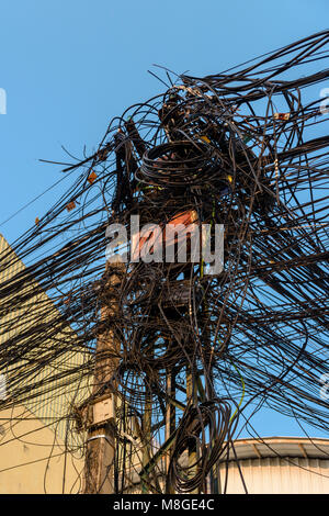 Strommast mit Dutzenden von gefährlichen ungepflegt unordentlich Kabel und Leitungen Stockfoto