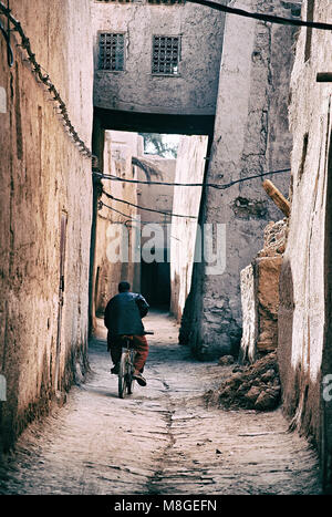 Mann reiten Fahrrad durch Gasse im Ksar, Marokko - Es ist ein markantes Beispiel für pre-Saharan marokkanische Architektur Stockfoto