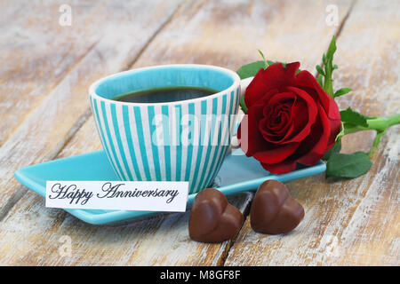 Herzlichen Glückwunsch zum Jubiläum Karte mit Tasse Kaffee, zwei herzförmige Pralinen und red rose Stockfoto