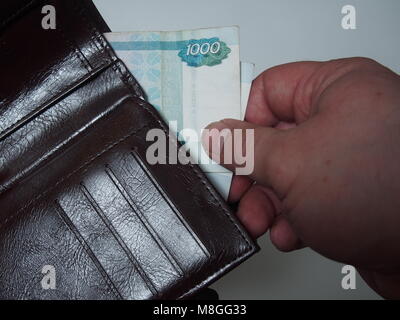 Eine Person zieht aus dem Geldbeutel Rechnung Nennwert von 1000 russischen Rubel. Close Up. Stockfoto