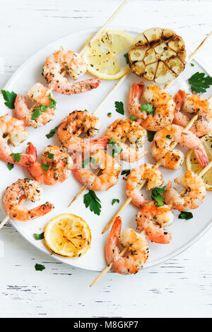 Gegrillte Garnelen Spieße. Meeresfrüchte, shelfish. Garnelen Spieße mit Gewürzen und frischen Kräutern auf weißem Hintergrund Holz, kopieren. Garnelen b Stockfoto