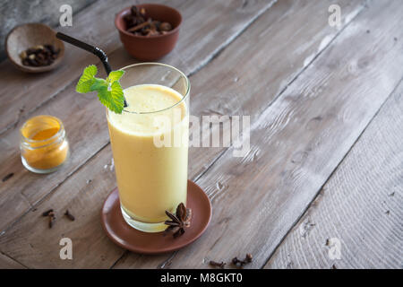 Gelbwurz Lassie oder Lassi aus Glas - gesunden probiotischen Indischen kaltes Getränk aus Quark (Joghurt), Milch, Gewürzen und Zucker. Gelbwurz Smoothie auf Holz, Stockfoto