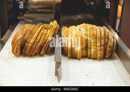 Frisch gebackenes Brot auf dem Förderband in Scheiben geschnitten. Stockfoto