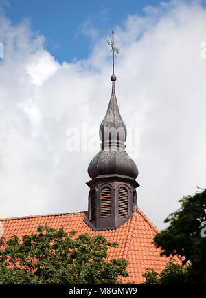 Goldenes Kreuz einer Kirche auf rotem Ziegeldach Stockfoto