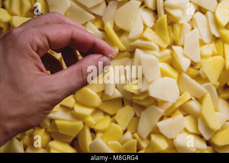 Pommes Frites mit Salz bestreut im Eimer. Die Nahaufnahme der Hand Salz frische Kartoffeln. Kochen Kartoffel Gerichte. Salz Hände. Stockfoto