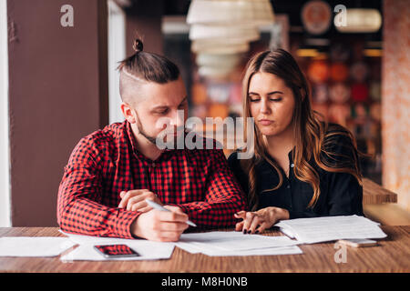 Junge Unternehmer einen Deal in ein Cafe, das Unterschreiben von Dokumenten Stockfoto