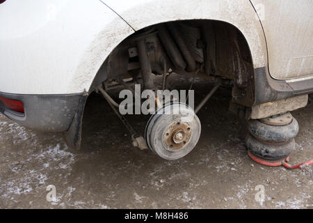 Low Angle Shot Seite Profil von Expert specialist Techniker Reifen, Reifen von hob Auto, bei auto Werkstatt, trägt kariertem Hemd, einheitliche Co Stockfoto