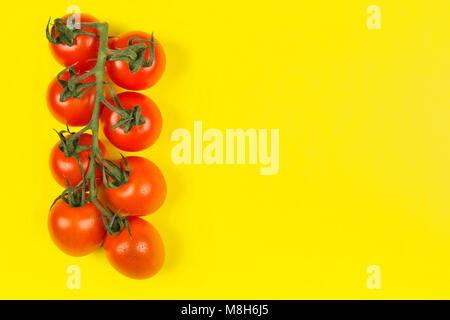 Rote Kirschtomaten auf gelben Hintergrund. Ansicht von oben, kopieren. Essen Hintergrund Stockfoto