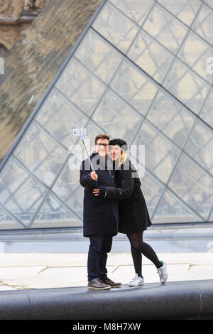 Ein paar nehmen selfies und Fotos an der Glaspyramide Eingang des Louvre in Paris, Frankreich Stockfoto