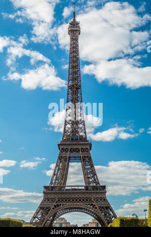 Blick auf den wunderschönen Eiffelturm unter grünen üppigen Bäumen im Sommer auf dem Hintergrund des blauen Himmels Stockfoto