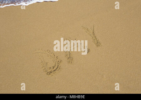 Tag im Sand am Meer Hintergrund geschrieben. Stockfoto