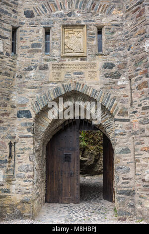 Dornie, Schottland - Juni 10, 2012: Nahaufnahme von Grau-Stein verbeugte sich Eingang zum Eilean Donan Castle mit beige Wappen oben. Braune Tür öffnen s angezeigt Stockfoto