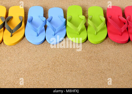 Flip Flops in einer Reihe auf einem Sandstrand. Platz für Kopieren. Stockfoto