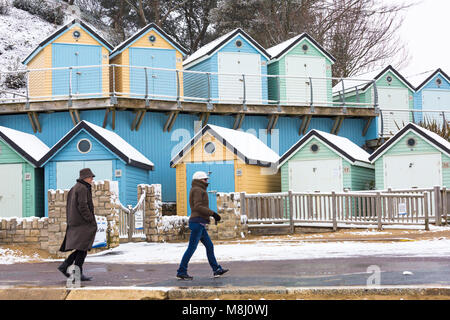 Bournemouth, Dorset, Großbritannien. 18. März 2018. UK Wetter: Tier aus dem Osten 2 bringt schwere Schnee am Strand von Bournemouth - Paar vorbei Snow Beach Hütten von Alum Chine Kredit abgedeckt: Carolyn Jenkins/Alamy leben Nachrichten Stockfoto