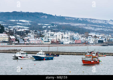 Lyme Regis, Dorset, Großbritannien. 18. März 2018. UK Wetter. Die Aussicht vom Cobb Hafen ein helles Abstauben von Schnee bedeckt, die die Dächer in Lyme Regis in Dorset an der Dämmerung abdeckt. Foto: Graham Jagd-/Alamy leben Nachrichten Stockfoto