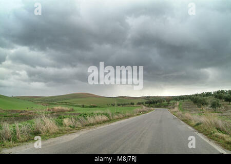 Lonely Kunst Natur Hügel auf der grünen Wiese und Asphalt unter bewölktem Himmel stürmisches Wetter Stockfoto