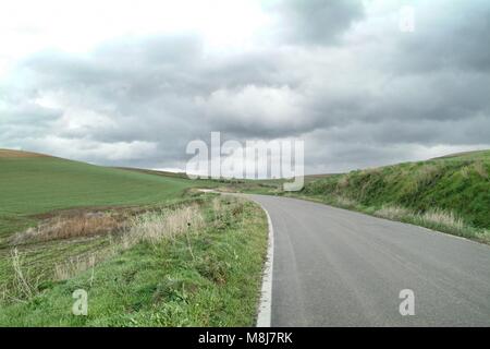 Lonely Kunst Natur Hügel auf der grünen Wiese und Asphalt unter bewölktem Himmel stürmisches Wetter Stockfoto