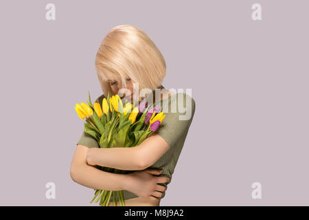 Schöne begeistert lächelnde Frau mit einem Blumenstrauß aus Tulpen auf grauem Hintergrund Stockfoto