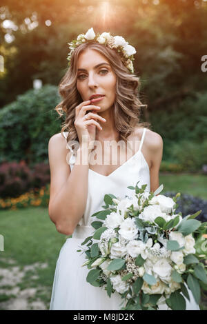 Schöne Mädchen in weißen Brautkleid Holding einen Strauß weißer Blumen, Braut in der Natur Stockfoto