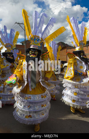 Männer in traditionellen Kostümen, Masken und Kopfbedeckungen in Gelb und Weiß, Festival Parade Stockfoto