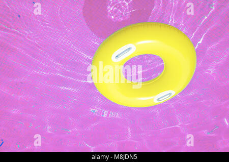 Gummiring floating in transparenten gefliesten Pool, in Rosa Stockfoto