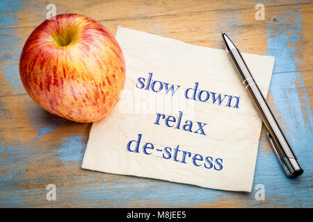 Slow down, Relax und de-Stress-Handschrift auf eine Serviette mit einem frischen Apfel Stockfoto