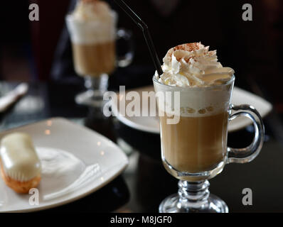 Kaffee mit Sahne und Eclair auf dem Tisch in einem Cafe Stockfoto