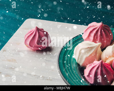 Pastellfarben rosa und weiß Baiser auf grünem Hintergrund. Weihnachten Magic Snow Fall Stockfoto