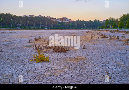 Den Sonnenuntergang Himmel über dem ausgetrockneten Fluss Zayandeh mit gecrackten Schlamm auf dem Boden und schönen Riverside Parks am Ufer, Isfahan, Iran. Stockfoto