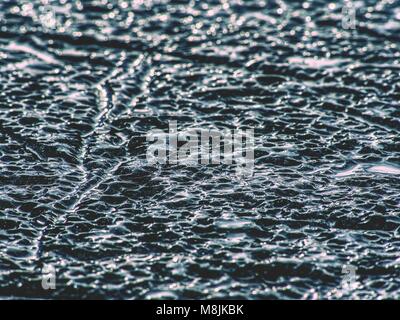 Eisschollen auf Schwarz felsigen Strand brechen. Risse im Eis auf schwarzem Sand Strand mit Allmählichen abschmelzen, winter Stockfoto