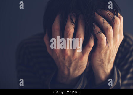 Hoffnungslos Drogensüchtigen seinen Kopf, Low Key Porträt mit selektiven Fokus Holding Stockfoto