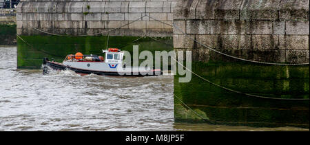 Massive verkettete's Tower Bridge cutwaters mit der Tug Boat gewidmet, der zwischen ihnen in abgehackt Thames Water Stockfoto