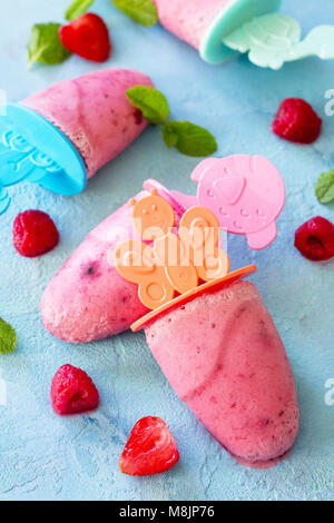 Kinder- Eis Eis am Stiel (rasberry Sorbet) auf Blau konkreten Hintergrund. Stockfoto