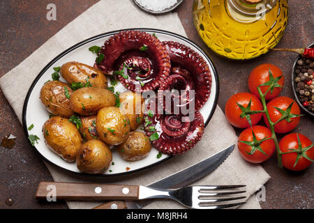 Gegrillter Tintenfisch mit kleinen Kartoffeln mit Kräutern und Gewürzen. Ansicht von oben Stockfoto