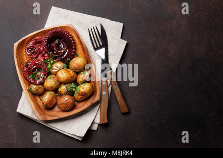Gegrillter Tintenfisch mit kleinen Kartoffeln mit Kräutern und Gewürzen. Ansicht von oben mit Platz für Ihren Text Stockfoto