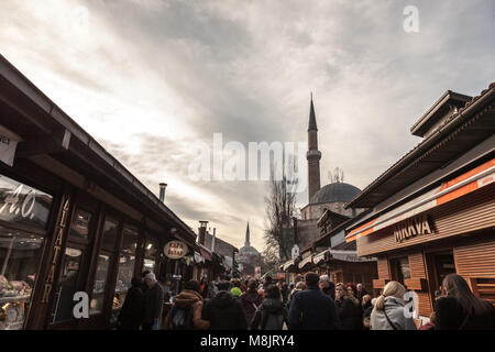 SARAJEVO, BOSNIEN UND HERZEGOWINA - 17. FEBRUAR 2018: die Straße voll mit Touristen und eine Moschee Minarett in der bascarsija Bezirk im Winter. Bascars Stockfoto