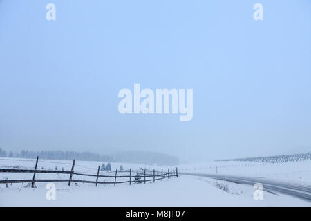 Weg bedeckt im Schnee in den bosnischen Bergen bei Sonnenuntergang, während eines schweren Winter Zustand Bild einer verlassenen Straße im Schnee im Winter fällt. Stockfoto