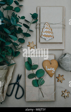 Verpackung Weihnachtsgeschenke mit Normalpapier und Lebkuchen Plätzchen mit Puderzucker auf ihnen Stockfoto