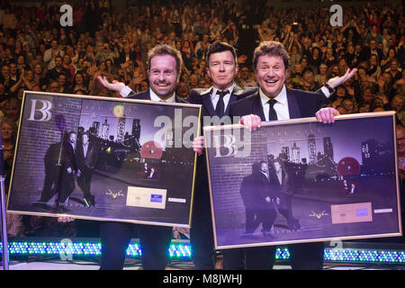 L-R: Alfie Boe, Rick Astley, Michael Ball. Rick Astley präsentiert Michael Kugel und Alfie Boe mit einer goldenen Cd live auf der Bühne während ihrer Leistung an der Eventim Apollo Hammersmith. Michael Ball und Alfies Boe Album 'zusammen' ging Gold in nur 15 Tagen. Stockfoto