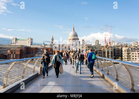 London, UK - April 2017: Menschen zu Fuß auf die Millenium Bridge der Themse mit Blick auf die St. Paul's Kathedrale an einem sonnigen Tag überqueren Stockfoto