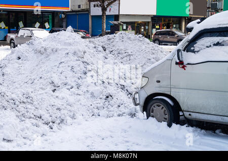 Die Folgen der Schneefall und Schneeräumen auf den Straßen der Stadt. Driftet auf der Fahrbahn und Parkplätze. Schnee Pfähle auf Autos Stockfoto