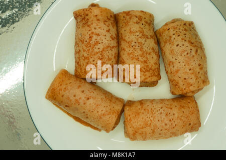 Kleine Pfannkuchen mit Honig, Himbeeren und Minze auf weißem Hintergrund gekrönt Stockfoto