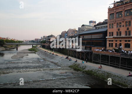 Die Menschen am Fluss Kamo Flussufer im Zentrum von Kyoto, Japan in der Abenddämmerung. Stockfoto