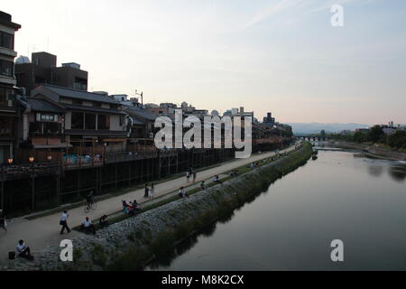 Die Menschen am Fluss Kamo Flussufer im Zentrum von Kyoto, Japan in der Abenddämmerung. Stockfoto