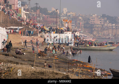 VARANASI, Indien. Februar 28, 2017: Ein typischer Tag an den Ufern des Flusses Ganges: Hindus brennen Leichen im Fluss gewaschen, die Zähne putzen Ein Stockfoto