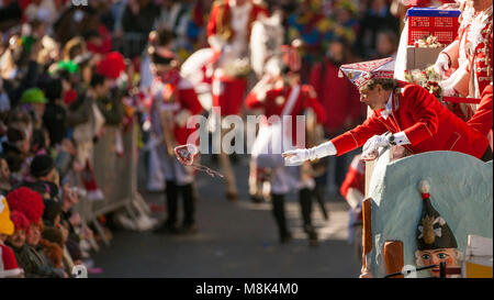 Karneval Clown am Rose Montag Parade in Köln wirft ein Lebkuchenherz in die Menge. Stockfoto