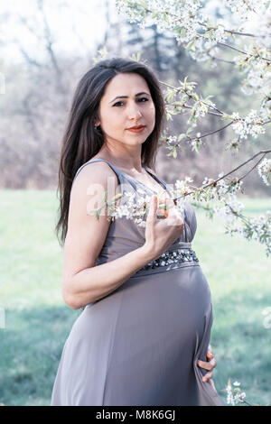 Schwangere Frau in einem blühenden Baum Stockfoto