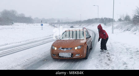 Ein Mitglied des Nordens Dartmoor Such- und Rettungsteam unterstützt ein Kraftfahrer auf einer Straße von der A 30 in der Nähe von Okehampton in Devon als schweren Schnee Verkehrschaos zu Teilen der South West gebracht. Stockfoto