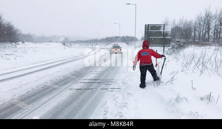 Ein Mitglied des Nordens Dartmoor Such- und Rettungsteam Uhren ein Autofahrer fahren entlang einer Straße in der Nähe von Okehampton in Devon als schweren Schnee Verkehrschaos zu Teilen der South West gebracht. Stockfoto